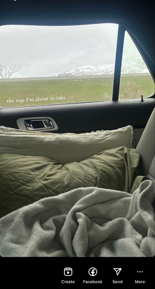 an image of the back seat of a car with blankets and pillows in front of it