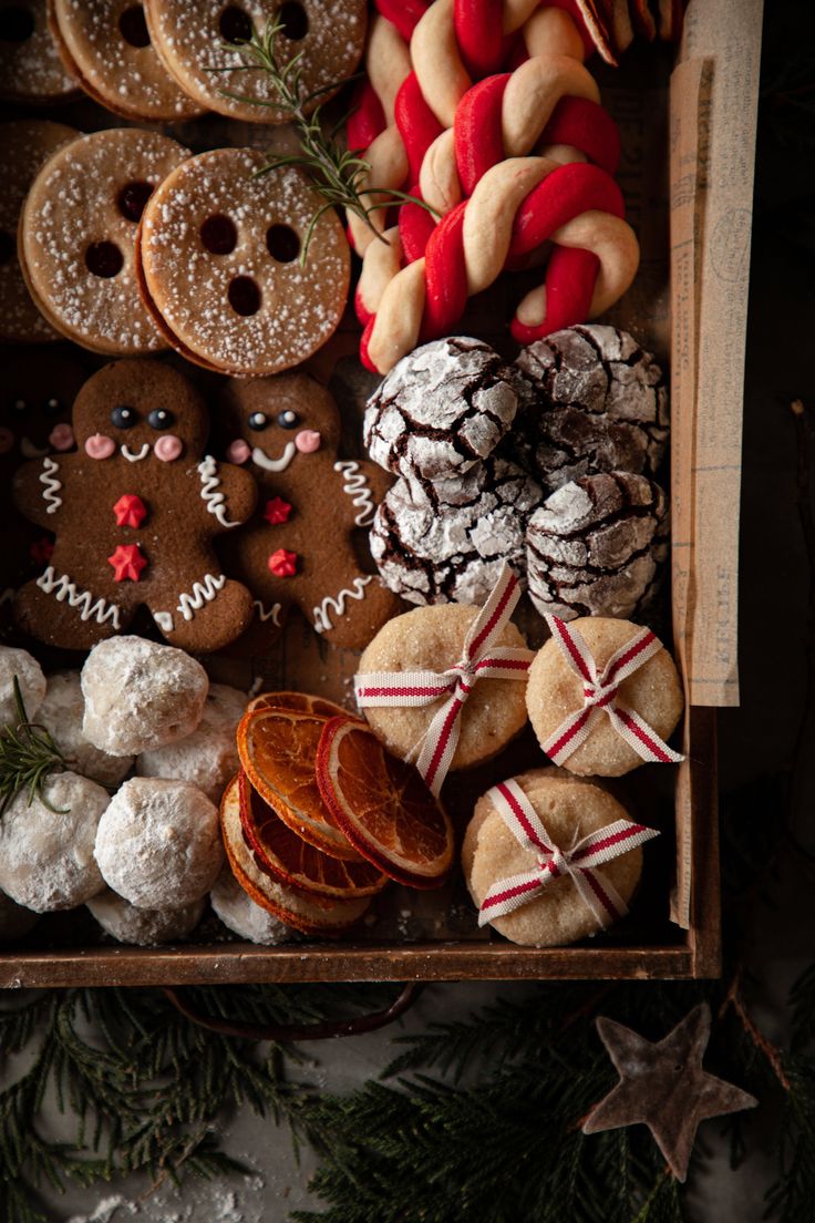 an assortment of christmas cookies and pastries in a wooden box with pine cones on the side