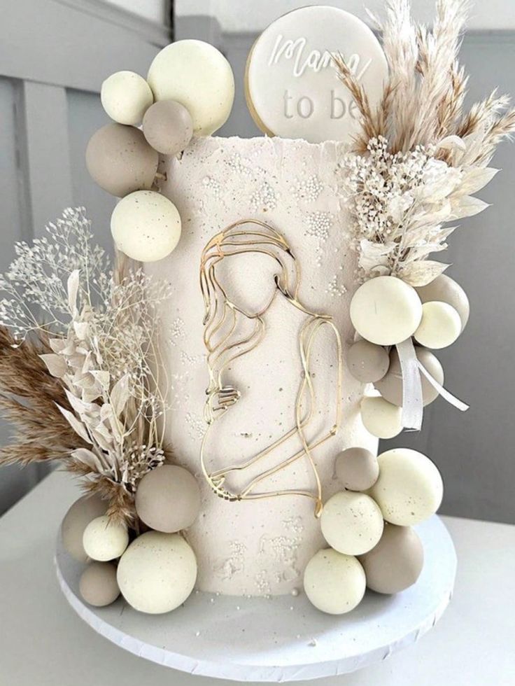 a white cake with frosting and some dried plants on it's side, sitting on top of a table