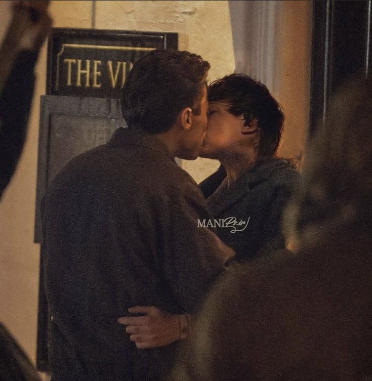 two people kissing each other in front of a sign