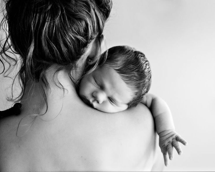 a black and white photo of a woman holding a baby in her arms, with the child's eyes closed