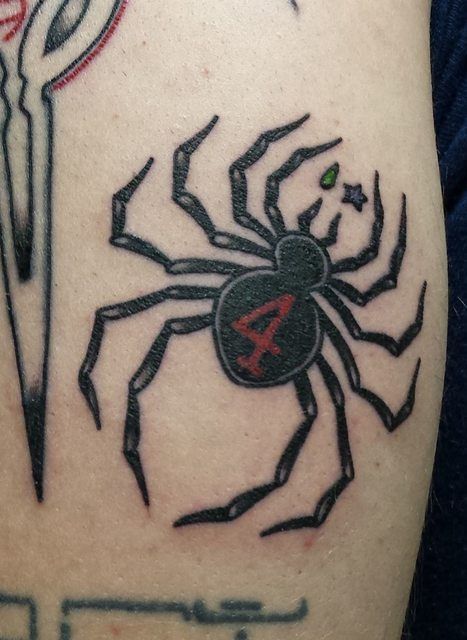 a spider tattoo on the back of a man's arm with an arrow in it