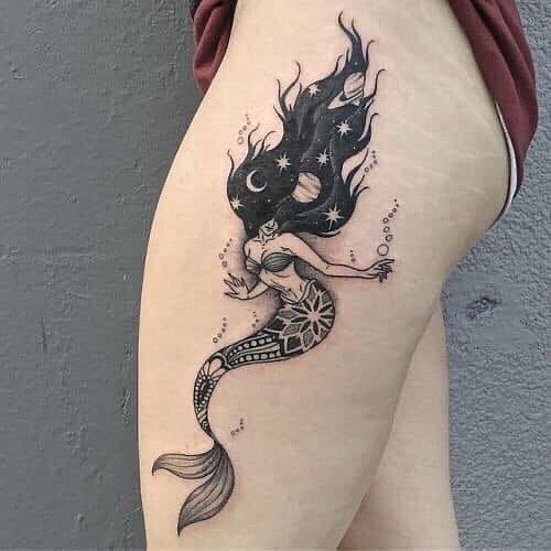 a woman's thigh with a tattoo design on her leg and a mermaid tail