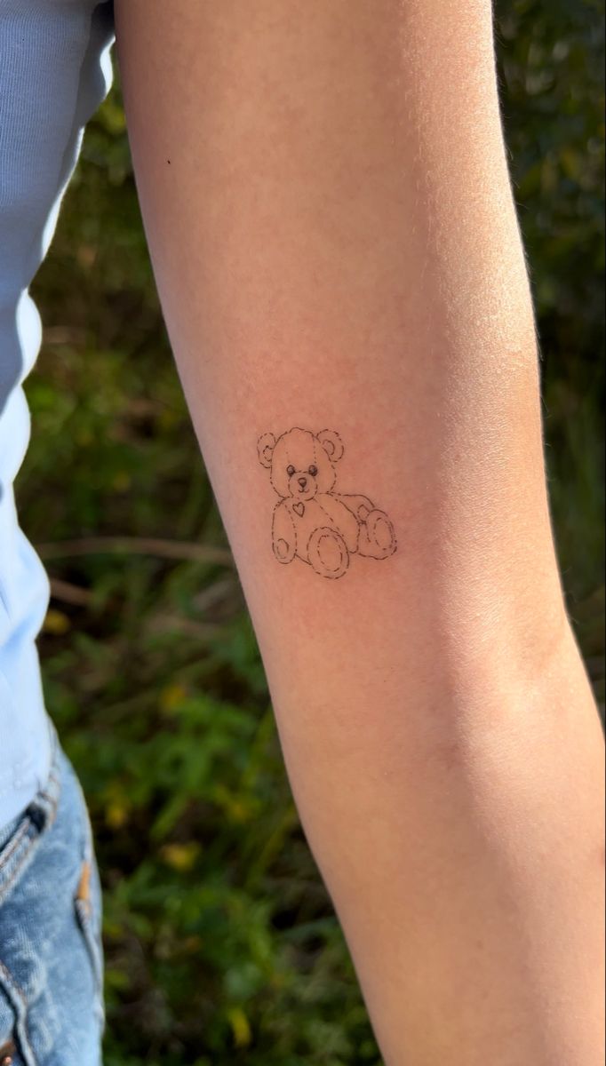 a small teddy bear tattoo on the arm