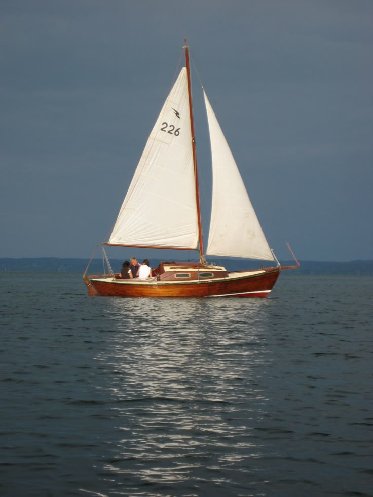 a sailboat with two people on it in the water