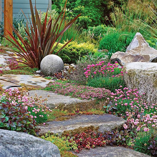 a garden with rocks and flowers in the foreground