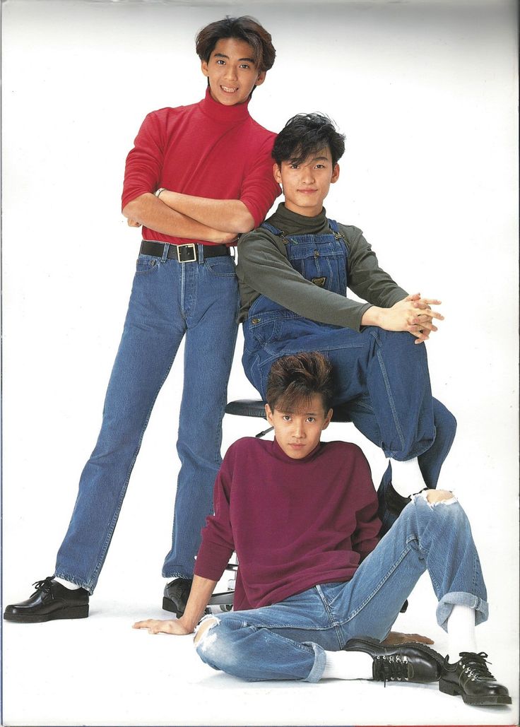 three young men sitting on the ground posing for a photo together, with their arms around each other