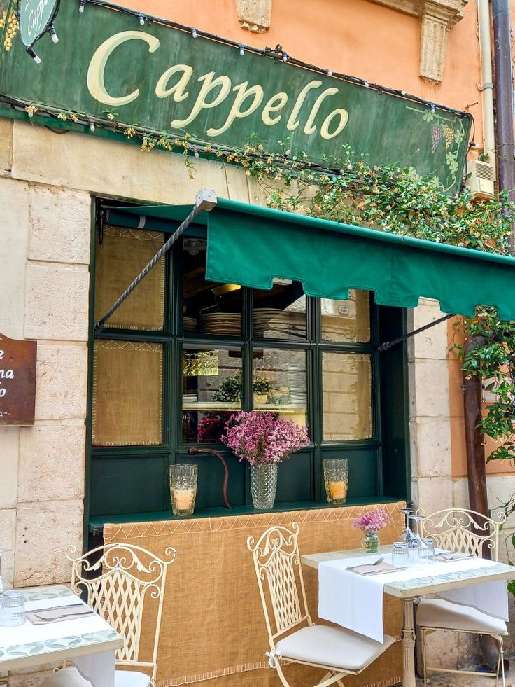 tables and chairs outside of a restaurant with green awnings on the front door