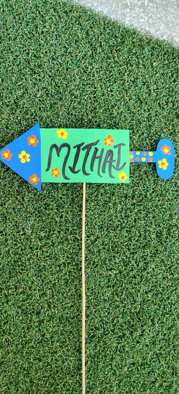 a blue and green sign that says mthirt on top of a wooden stick