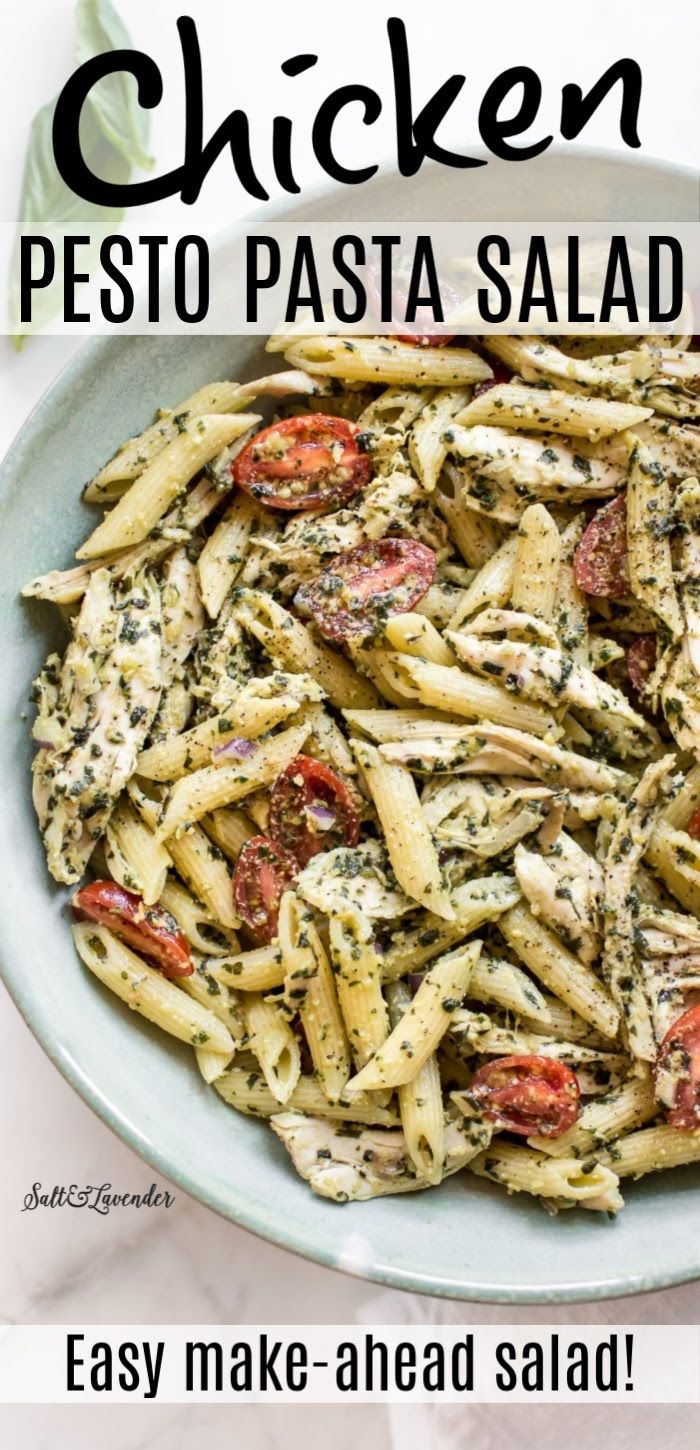 pasta with pesto and tomatoes in a bowl on a white tablecloth next to basil leaves