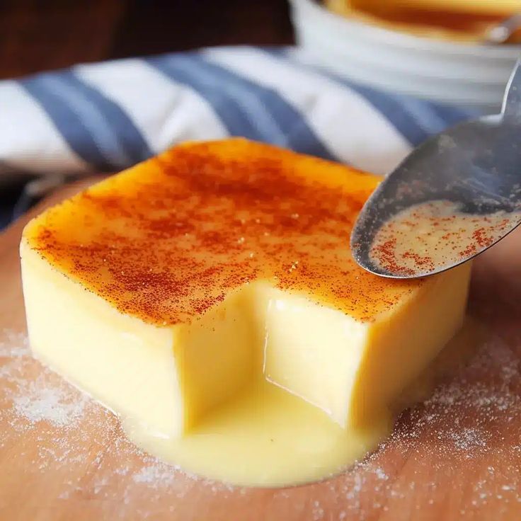 a wooden cutting board topped with cheese and a spoon