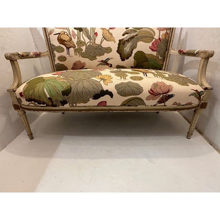 an old style couch with flowers and leaves on the back is sitting against a wall