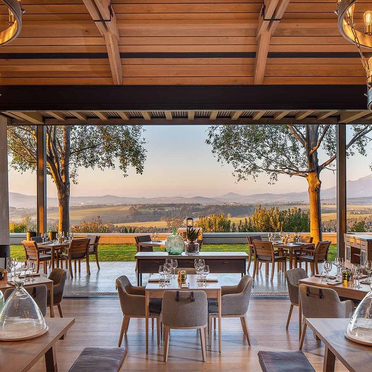 an outdoor dining area with wooden tables and chairs, overlooking the valley in the distance