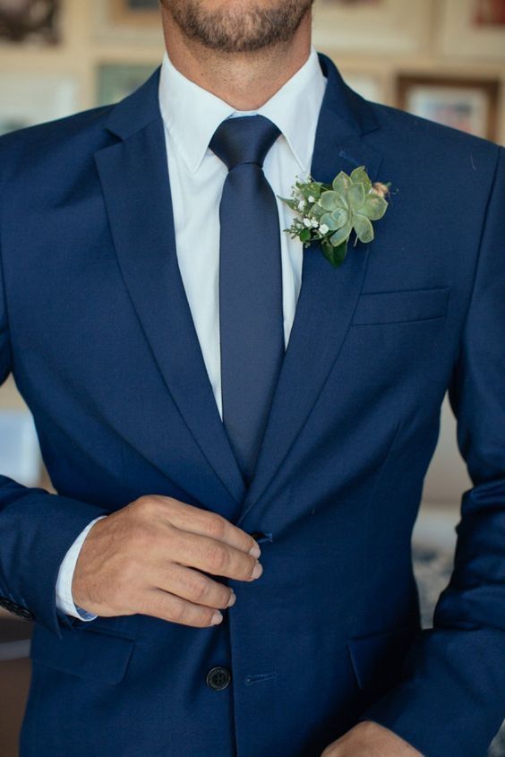 a man in a blue suit with a boutonniere on his lapel