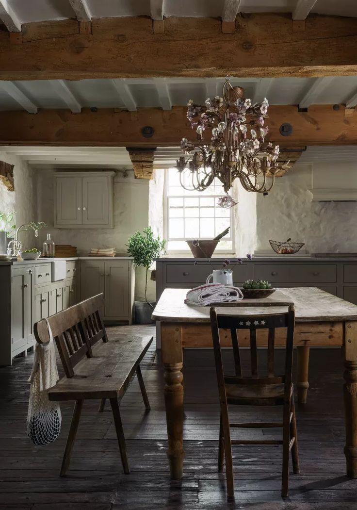 a table and chairs in a room with wooden beams on the ceiling, chandelier hanging from the ceiling