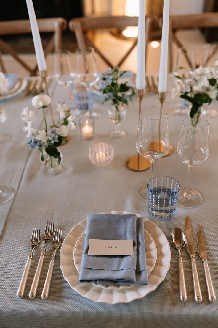 the table is set with silverware, candles and place settings for dinner guests to enjoy