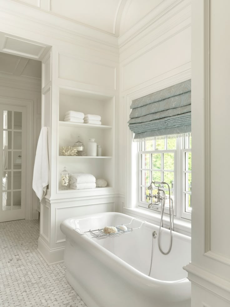 a white bathroom with a tub and window