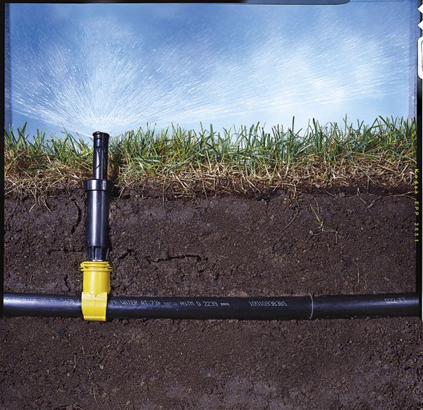 a yellow and black fire hydrant sitting in the middle of a dirt field next to a pipe