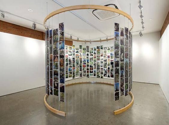 an art installation with multiple pictures on the wall and hanging from the ceiling in a circular room