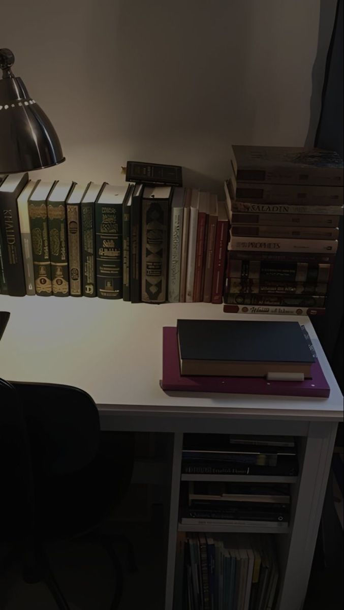 a white desk topped with lots of books next to a lamp