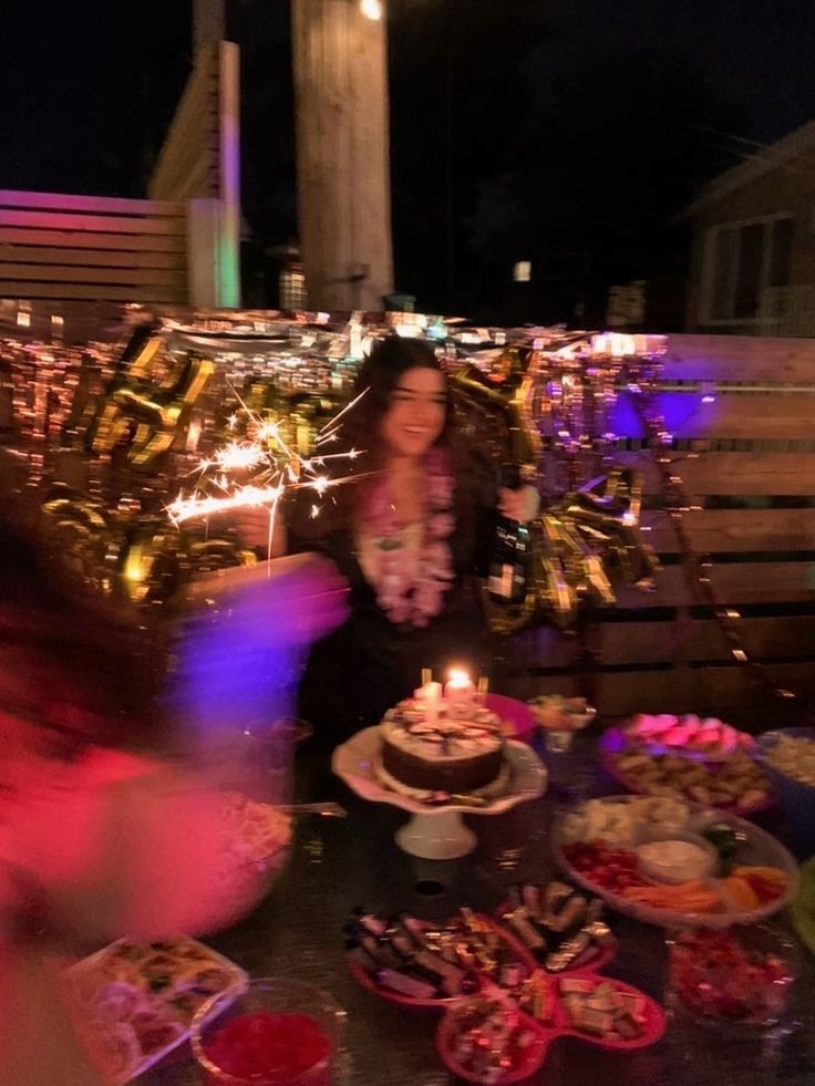 a woman sitting at a table with a cake and candles in front of her on it