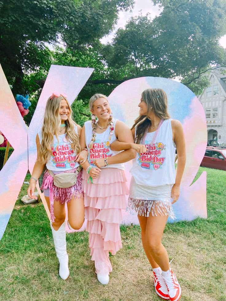 three girls standing in front of a giant letter