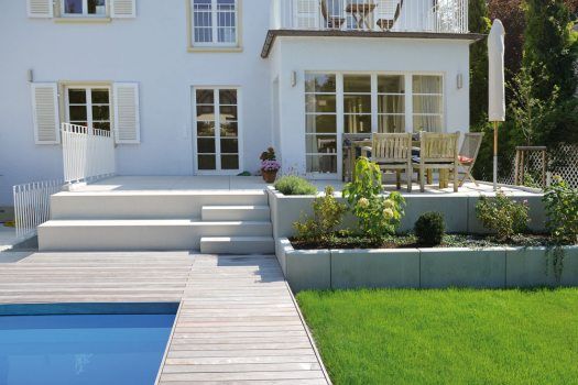 a house with a swimming pool in front of it and a deck leading to the back door