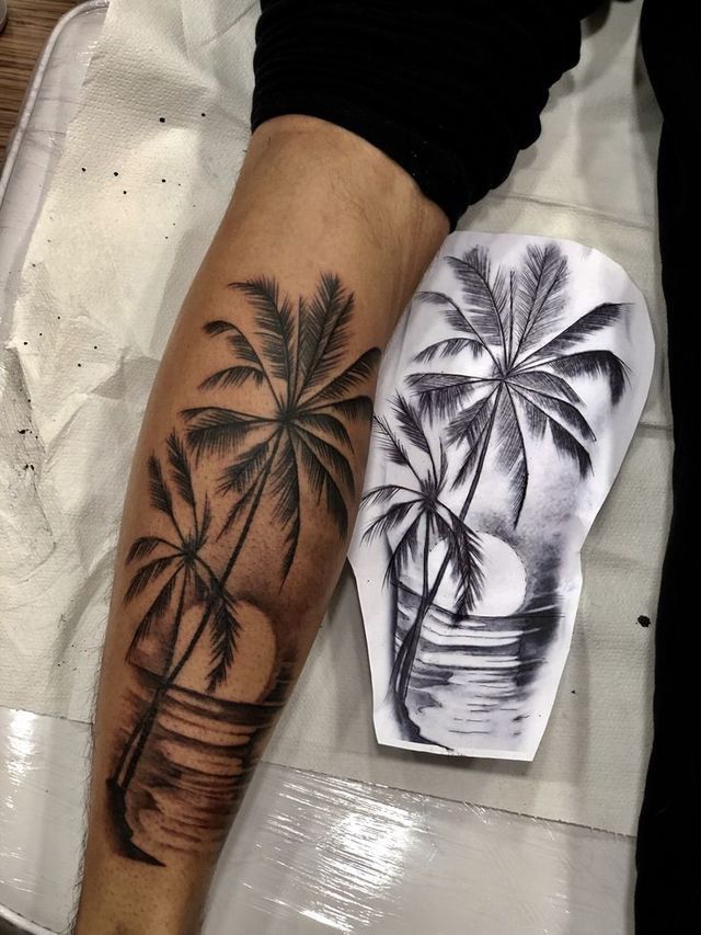 a man's arm with a palm tree tattoo on it, next to a piece of paper