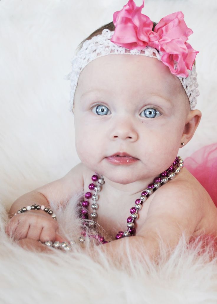 a baby girl with blue eyes wearing a pink headband