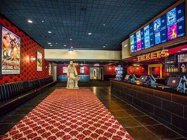 the inside of a restaurant with red and black walls, large screen tvs on the wall