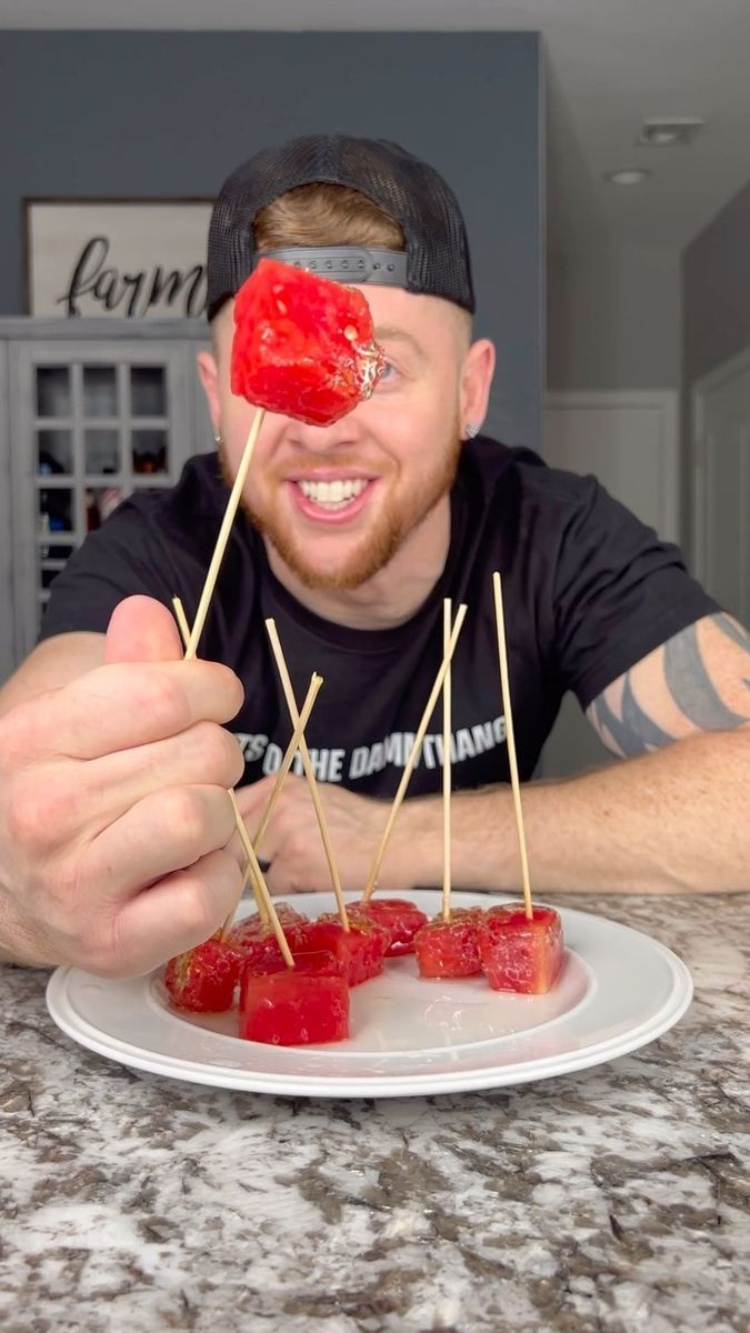 a man is holding up toothpicks with tomatoes on them