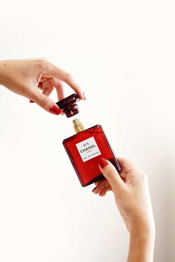 two hands reaching for a bottle of perfume