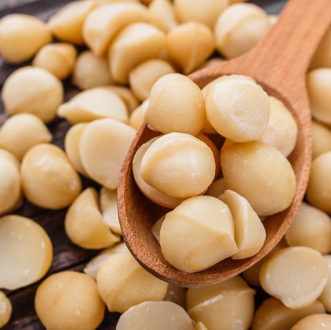 a wooden spoon filled with peeled beans on top of a table