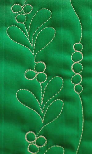 a green piece of fabric with white stitching on it and some circles in the middle