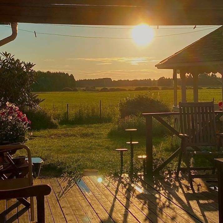 the sun is setting over an outdoor deck with chairs and tables in front of it