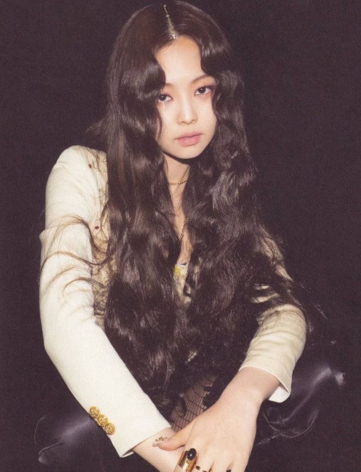 a woman with long dark hair sitting on a chair