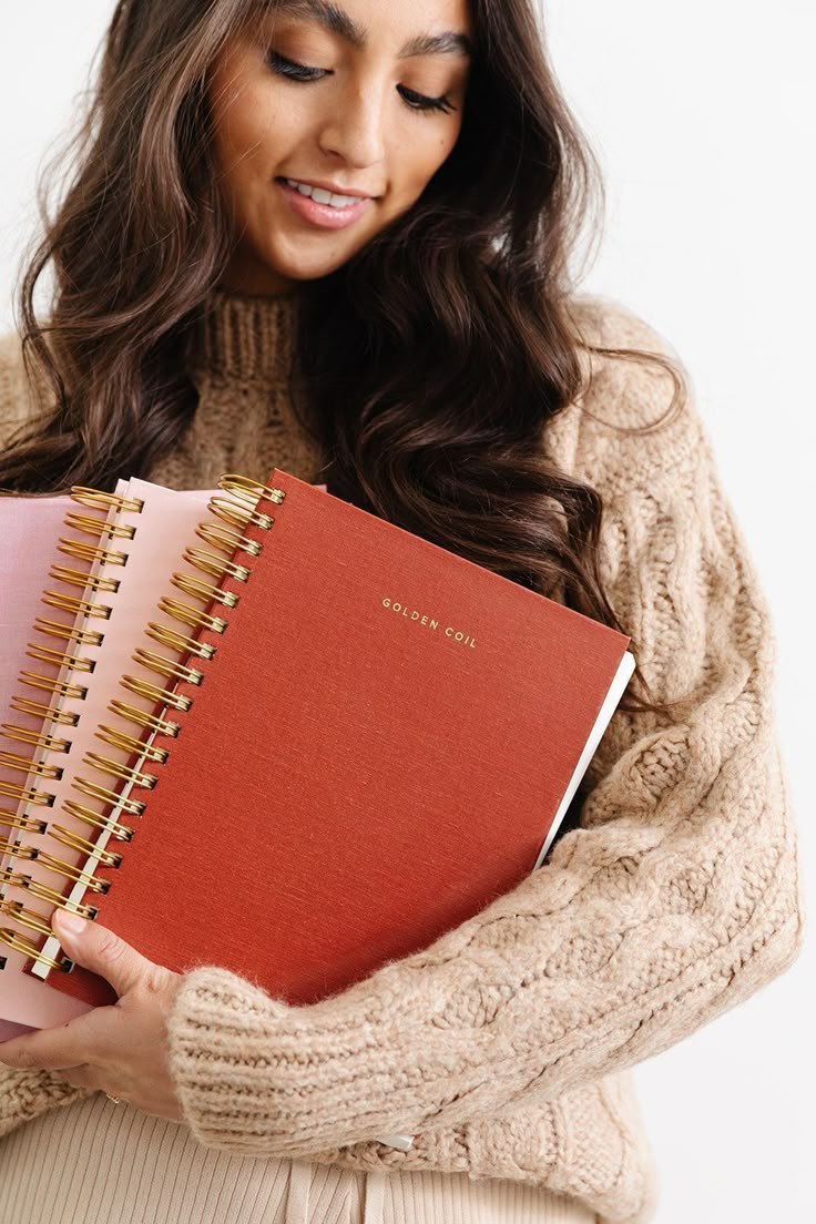 a woman holding two notebooks in her hands