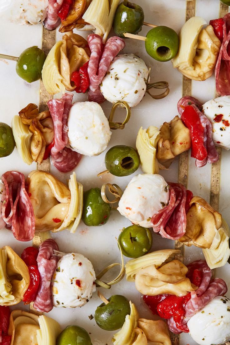 many different types of food on skewers with olives