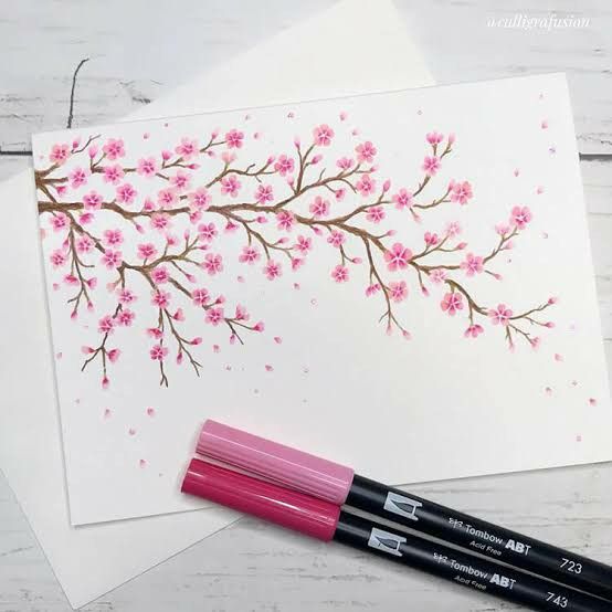 two pens are sitting on top of some paper with flowers painted on it and one is pink