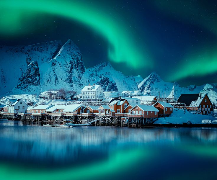 the northern lights shine brightly over houses and snow - capped mountains in this winter scene