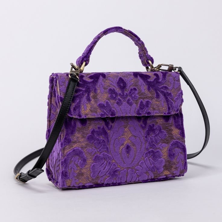 With a nod to the Victorian era, MCW's freshly combines the classic and elegant design of the traditional carpet satchel with a textural and tactile twist. This exquisite top handle satchel is a perfect blend of style and practicality. Spacious interior with zipper and slip pockets, detachable shoulder strap. Sturdy exterior in carpet or velvet, cotton lining. Convenient magnetic flap closure, brass feet for stability. Features: * Detachable, adjustable shoulder strap * Magnetic flap for easy access * Interior slip and zipper pockets * Hand-polished brass hardware * Includes dust bag Dimensions: * Satchel size: 9.50"W x 4"D x 8"H * Adjustable shoulder strap: 43.50" to 51.15" Interior Pockets: * Zipper pocket: 7"W x 5"H * Slip pocket: 8"W x 5.50"H Weight: 1lb 5oz Luxury Rectangular Flap Bag With Adjustable Handle, Luxury Rectangular Satchel With Adjustable Handle, Classic Purple Bag With Detachable Handle, Luxury Purple Satchel With Top Carry Handle, Classic Purple Rectangular Bag, Classic Purple Bag With Top Carry Handle, Classic Purple Top Handle Shoulder Bag, Vintage Formal Satchel With Adjustable Handle, Classic Purple Shoulder Bag With Detachable Handle