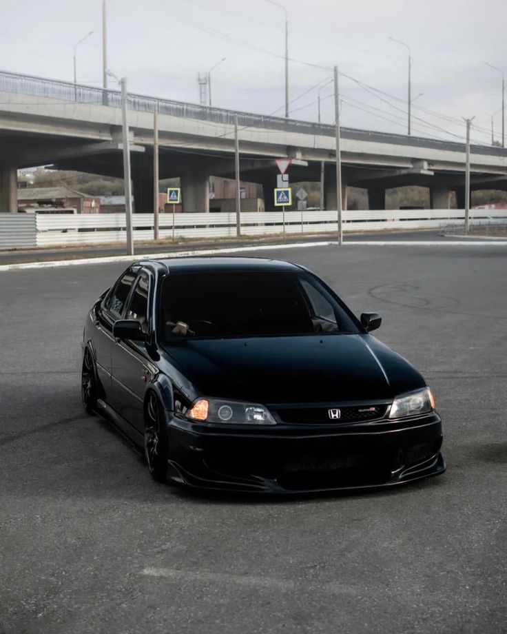 a black car is parked on the side of the road in front of an overpass