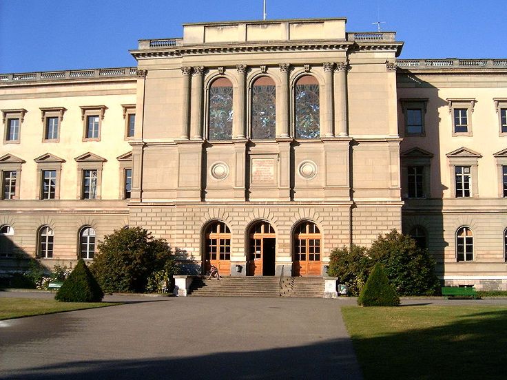 a large building with many windows on the top floor and two flags flying above it