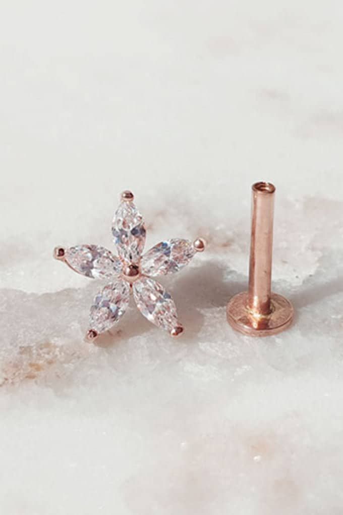 a pair of earrings sitting on top of a snow covered ground next to a screw