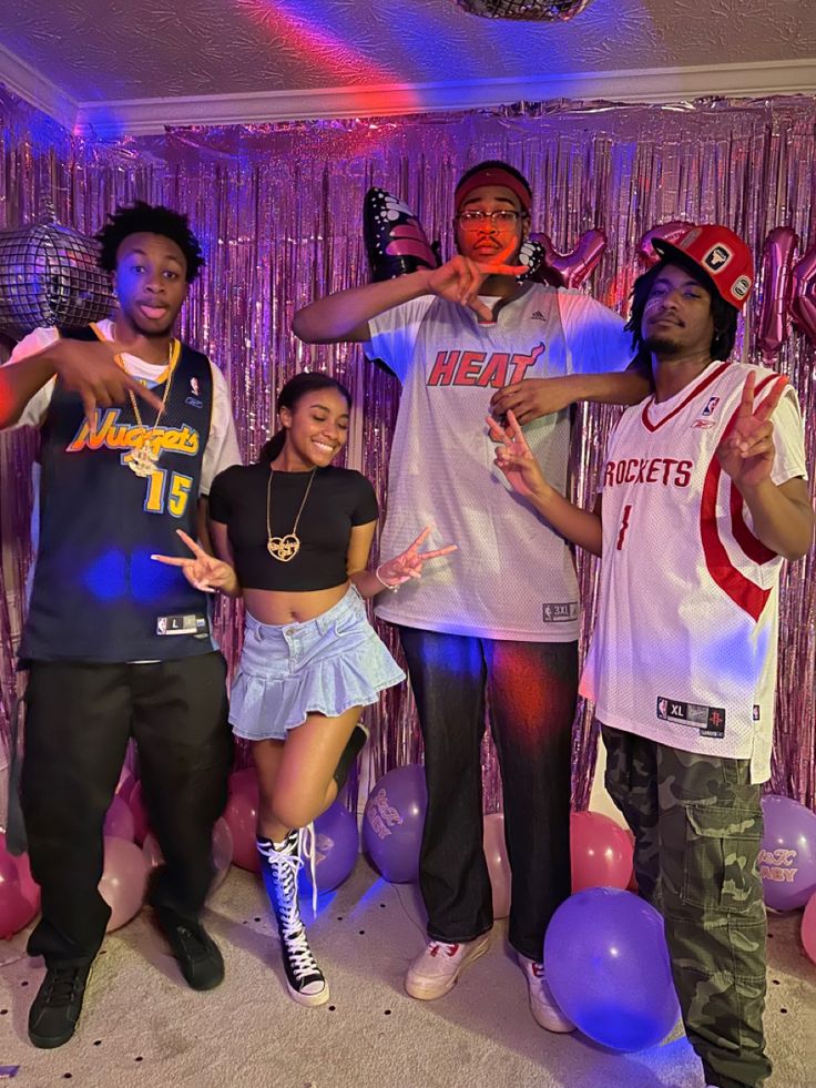 four people posing for a photo in front of balloons and streamers at a sports themed birthday party