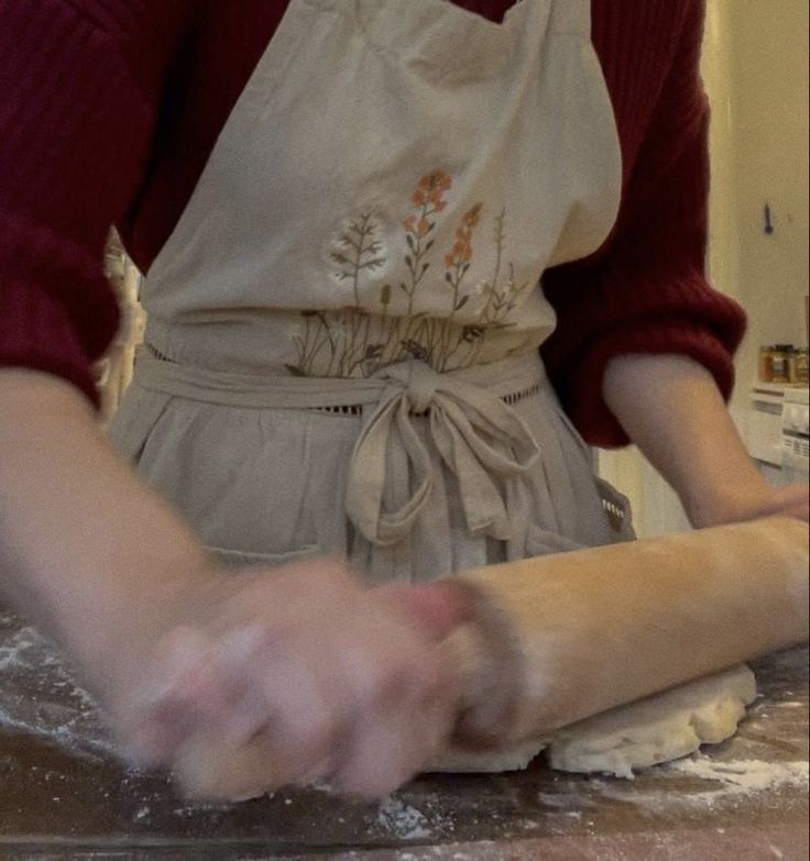 a woman in an apron is kneading dough