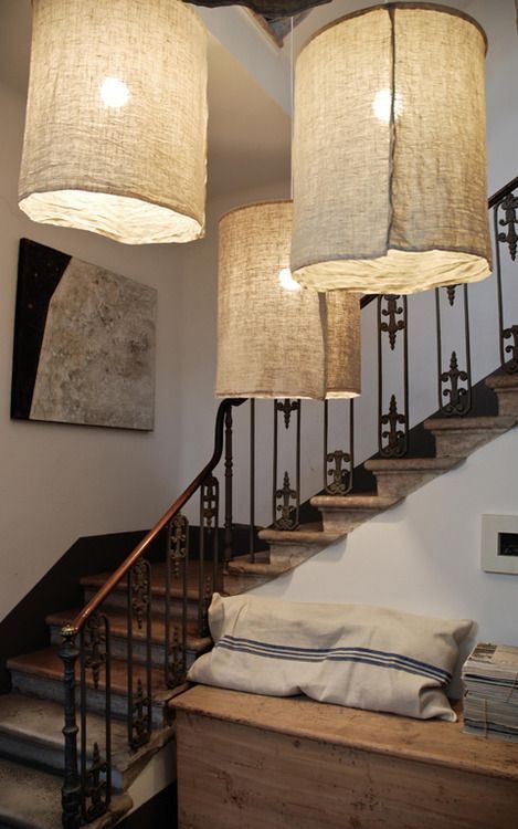 three lamps hanging from the ceiling above a bed in a room with white walls and stairs