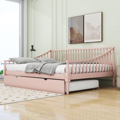 a pink day bed sitting on top of a hard wood floor next to a window