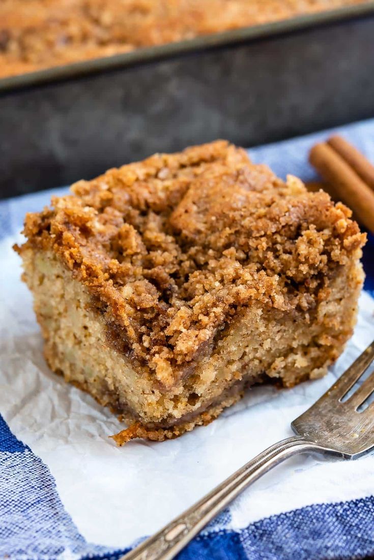 a close up of a piece of cake on a napkin with two cinnamon sticks next to it