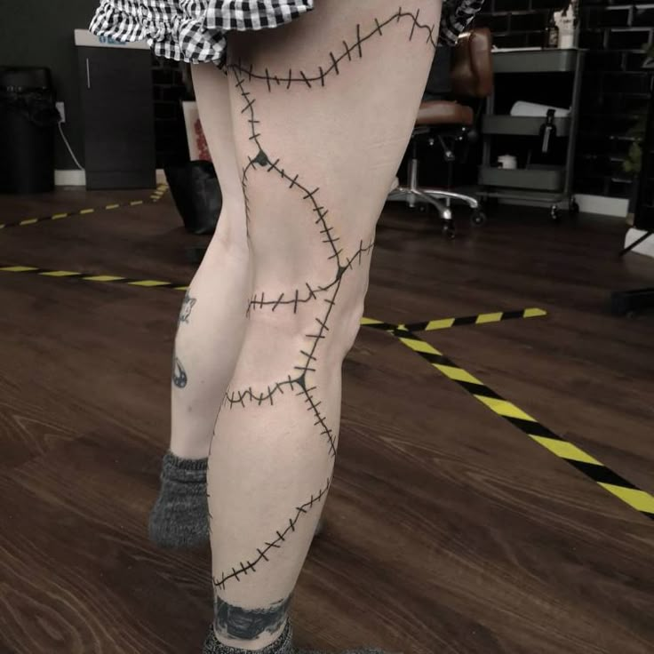 a woman with tattoos on her legs and leggings that are covered in barbed wire